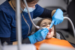 Girl in the dentist's office. Dentist examining child patient's teeth. High quality photo. Girl with open mouth at the dentist. Dentistry concept. Dental treatment at a specialist.